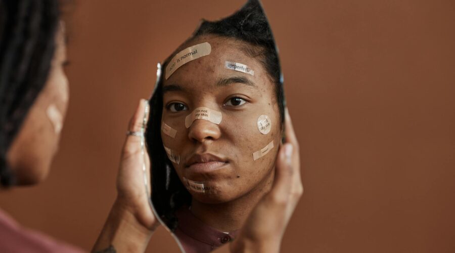 a sad woman looking at herself on a broken mirror she is holding